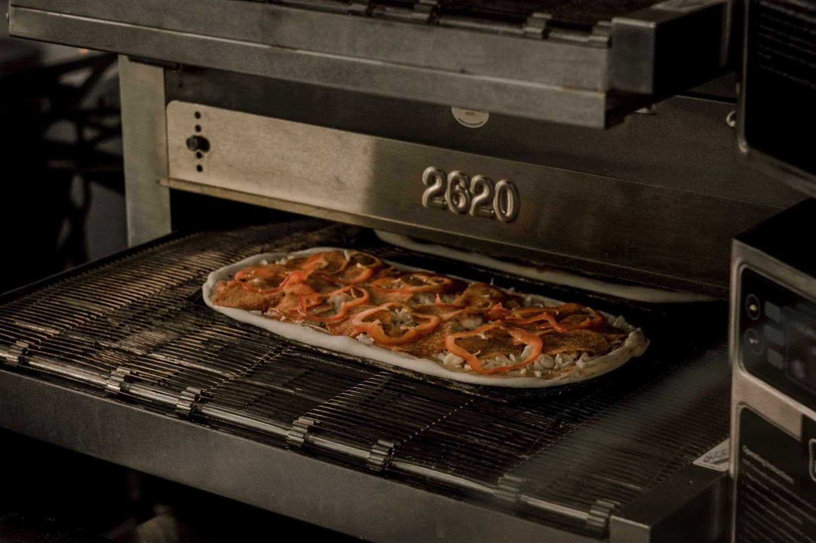 Pizza med paprika og kjøtt som stekes i en stor ovn