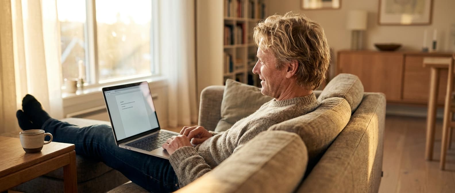 Person som tester gratis AI-chatverktøy avslappet hjemme på sofaen med kaffe